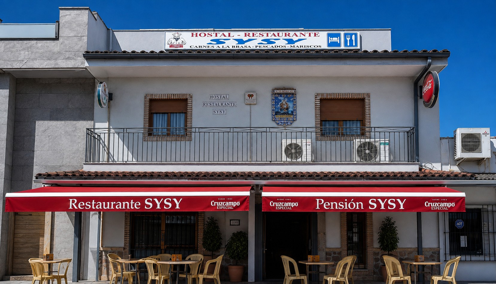 Fachada del Hostal Restaurante Sysy en Villanueva de la Reina, con toldos rojos y terraza